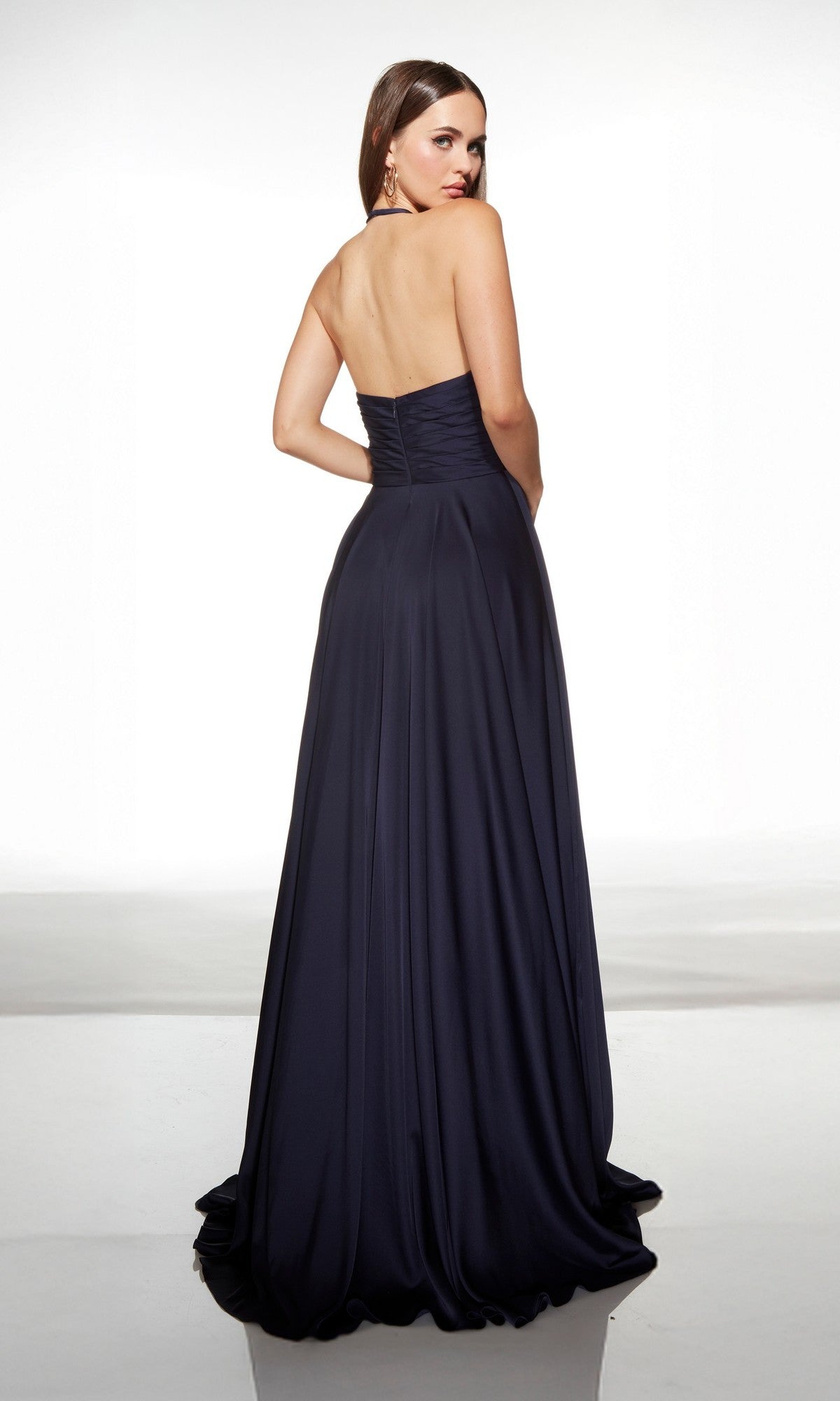 A woman faces away, wearing the Alyce 62152 Long Prom Dress—a floor-length navy satin gown with a fitted bodice and flowing skirt.